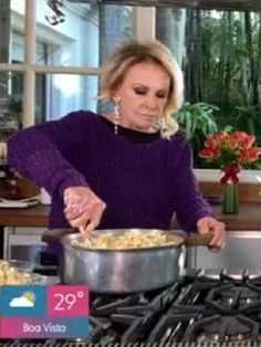 a woman is cooking in the kitchen with a pot