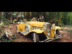 an old yellow car is parked in the woods