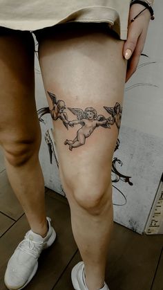 a woman's leg with tattoos on it and an image of cherubs