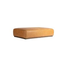 a brown leather ottoman sitting on top of a white wall