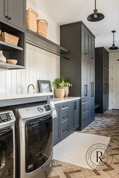 a washer and dryer are in the middle of a kitchen with gray cabinets