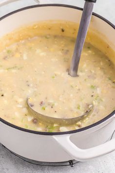 a pot filled with soup on top of a counter next to a wooden spoon in it