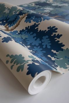 a blue and white wallpaper with flowers on it's back side, next to a roll of tape