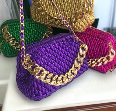 four different colored purses sitting on top of a white counter next to each other