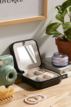 an open camera sitting on top of a wooden table next to other items and a potted plant