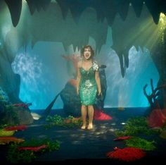 a woman in a green dress standing on stage