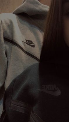 a woman with long hair wearing a nike hoodie