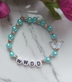 If you are a Dolly Parton fan, or know someone who is, here is the perfect gift. WWDD (What would Dolly do) bracelet features baby-blue faux pearls and a holographic butterfly because that's what Dolly's symbol! This is handmade at the time of order and is made using high-quality stretchy cord and beads. However, they are delicate, and I recommend you do not wear while sleeping, swimming, bathing, or working out.   One size fits most. Standard bracelet size is 7 inches. If you need a custom size Holographic Butterfly, Holographic Bag, Silver Wrapping Paper, White Jewelry Box, Pink Bubbles, Butterfly Jewelry, Bracelet Beaded, Women Gifts, Dolly Parton