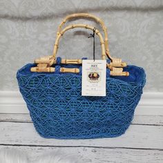 a blue woven basket with bamboo handles on a white wooden floor next to a wall