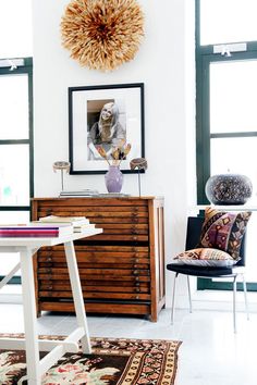 a room with a table, chair and pictures on the wall above it that has a rug in front of it