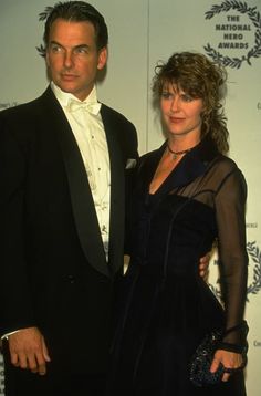 a man and woman standing next to each other in front of a white wall at an event