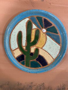 a blue and white plate with a cactus in the center on a tan background,