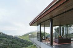 a living room with glass walls overlooking the mountains