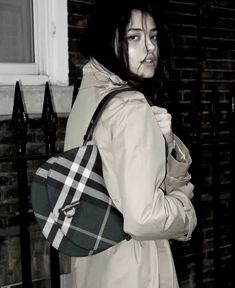 a woman in a trench coat carrying a purse