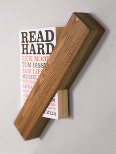 a close up of a wooden shelf on a wall with newspaper behind it and a book in the background