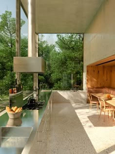 an outdoor kitchen and dining area in a modern house with large windows overlooking the trees