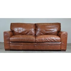 a brown leather couch sitting on top of a cement floor