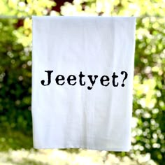 a tea towel with the word jeetyt on it hanging from a clothes line