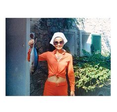 a woman in an orange outfit holding a fish