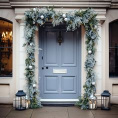 a blue front door decorated with greenery and christmas lights for an elegant entrance to a house