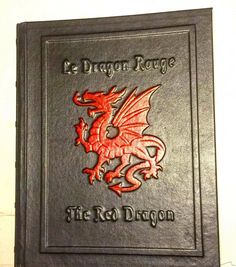 the red dragon logo is on top of a black leather book with silver lettering that reads,