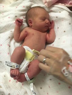 a baby laying on top of a bed being held by someone