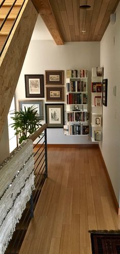 a long hallway with wooden floors and bookshelves on the wall next to stairs