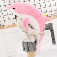 a girl is holding a pink dolphin pillow