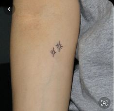 a small cross tattoo on the arm