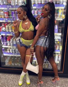 two women in bikinis standing next to each other near a display case with drinks