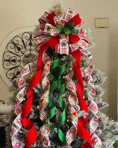 a decorated christmas tree with red, green and white ribbons on it's top