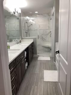 a bathroom with two sinks and a large mirror in the middle of it, next to a walk - in shower