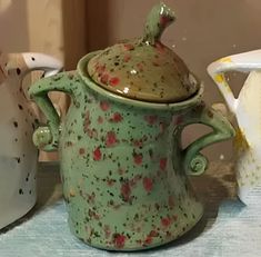 three ceramic pots sitting on top of a table next to each other and one has a lid