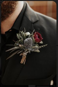 a man wearing a black suit and red flower boutonniere on his lapel