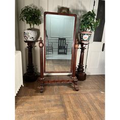 a large mirror sitting on top of a wooden floor next to two vases and a chair