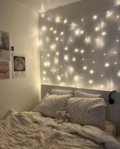 a bed with white sheets and lights on the wall