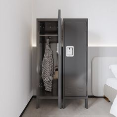 an open locker next to a bed in a room with white walls and flooring