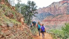 three people hiking up a trail in the mountains