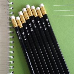 four black and gold pens sitting on top of a green notebook next to each other