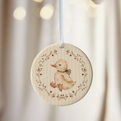 a wooden ornament with a duck on it's side hanging from a string