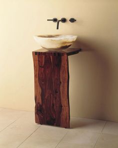 a bathroom sink sitting on top of a wooden pedestal next to a wall mounted faucet