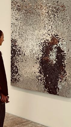 a woman standing in front of a large piece of art that is hanging on the wall