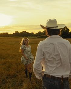 a man and woman standing in a field at sunset