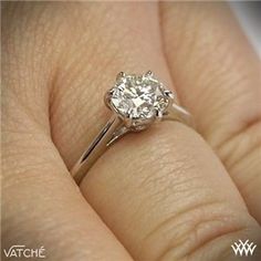 a close up of a person's hand with a diamond ring on their finger