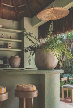 an outdoor bar with two stools and a potted plant on the counter in front of it