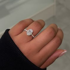 a woman's hand with a diamond ring on her finger and white nail polish