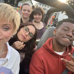 a group of people sitting next to each other in front of a car with the sun shining on them