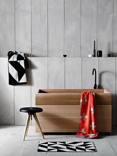 a modern bathroom with black and white tiles on the floor, wooden cabinets and stools