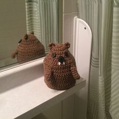 a crocheted teddy bear sitting on top of a counter next to a mirror