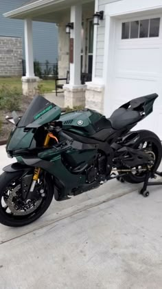 a green motorcycle parked in front of a garage with a white door and two windows